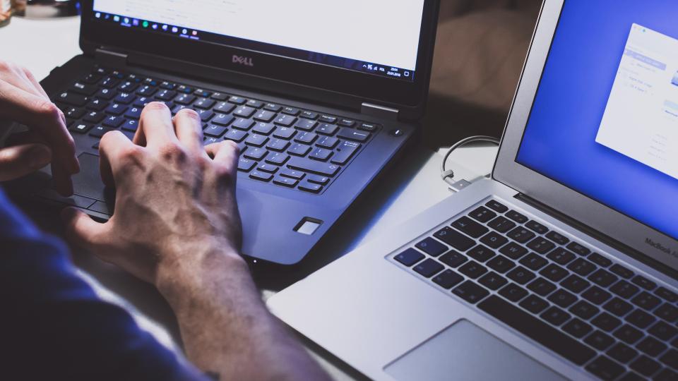 hand at two open laptops