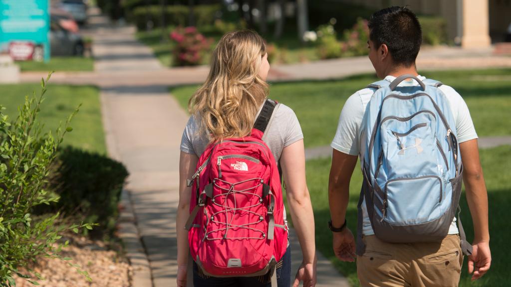 Backs of two students walking on the Pueblo Campus