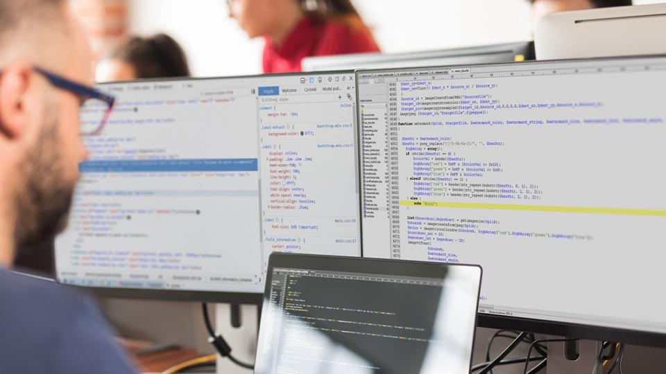 male working at computer with double monitors