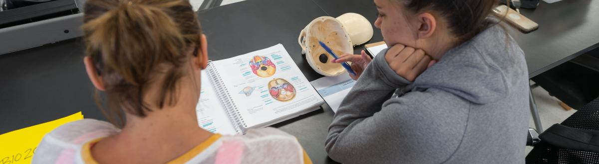 2 female students looking at book