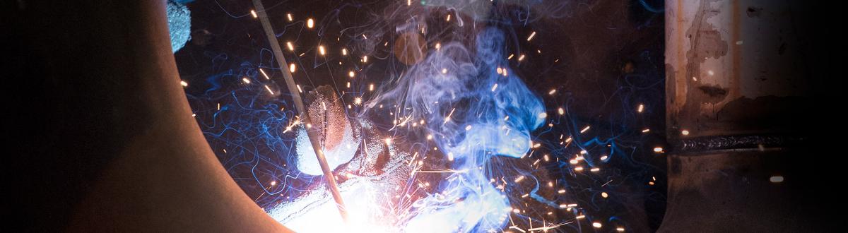 welding student surrounded by colorful welding sparks and smoke