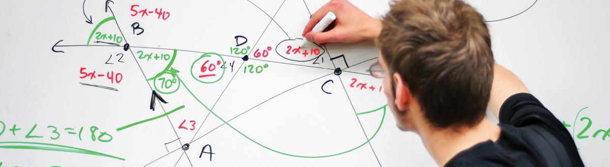 student writing math equations on whiteboard