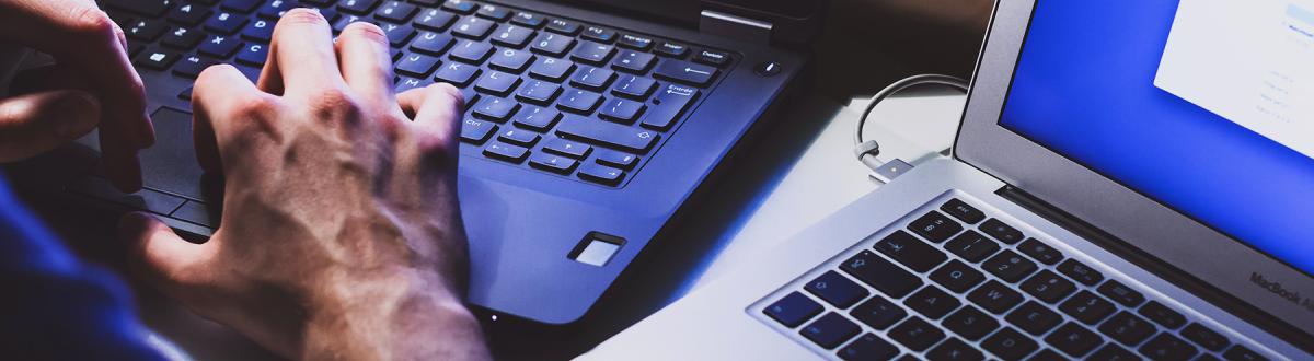 hands working at two different computers